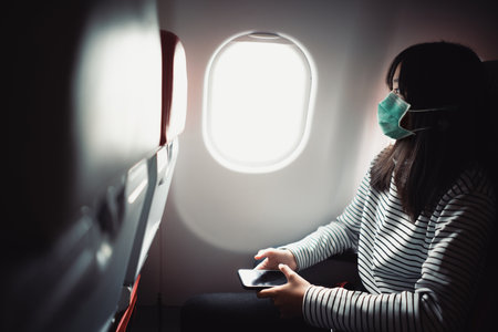 Teenage passenger wearing mask for protection Covid-19 While Sitting In Airplane.の写真素材