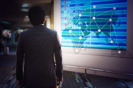 Man at the Airport with Virtual Worldmap and airlines schedule trafic