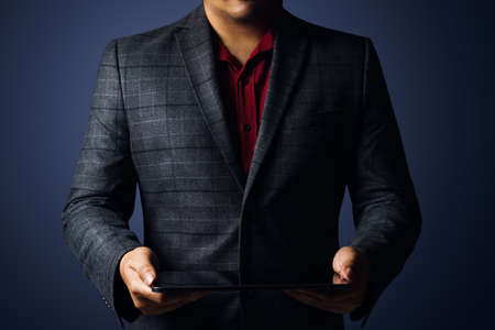 Cropped Image Of Businessman Holding Digital Tablet Against Gray Backgroundの写真素材