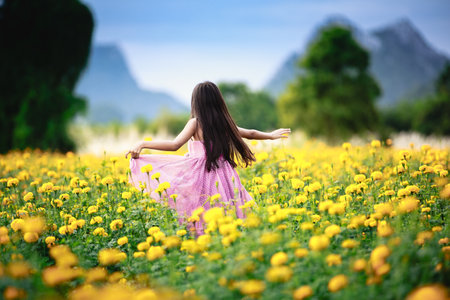 Happy little girl running on the marigold fieldの写真素材