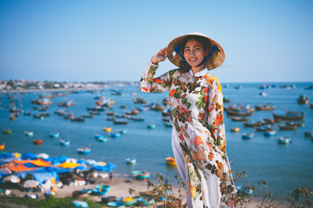 Vietnamese lady with Ao Dai Vietnam traditional dress and conical hat wait at the harbor, Fishing Harbour Mui Ne Vietnamの写真素材