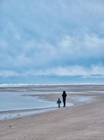 Small moment of contemplation for this mother and her child, in the middle of the gulls, gaze turned towards the seaの写真素材