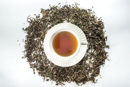 White cup of tea with dried tea leaf on the white backgroundの写真素材
