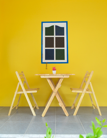 wooden table and chairs with yellow wall backgroundの写真素材