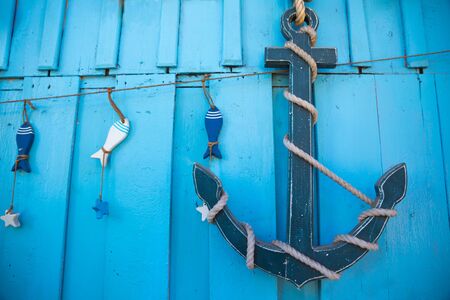 Wooden anchor and rope hanging on a  blue wooden wall   /sea travel conceptの写真素材