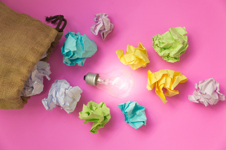 Inspiration concept with crumpled paper  and light bulb on pink background