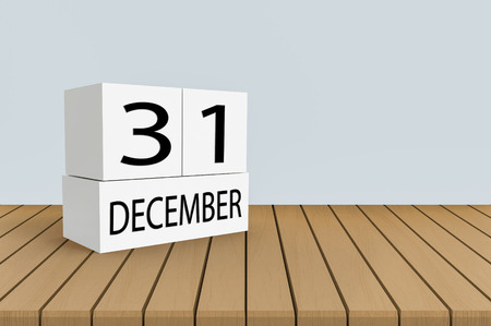 December 31 white cube calender on wood panel table with copy space gray wall background.の写真素材