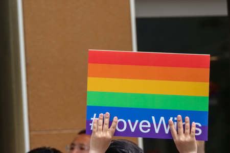 2017 MAY 08. TOKYO JAPAN. Human hand holding lgbt rainbow flag with LoveWins hastage and walking...