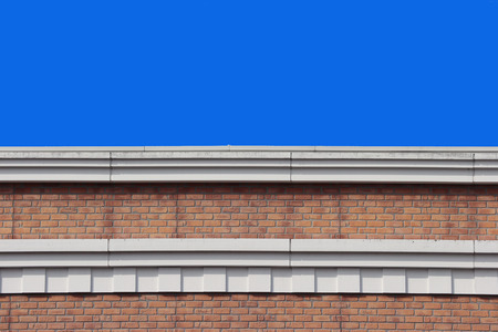 Top part of high brick stack wall design building with clear blue sky background.