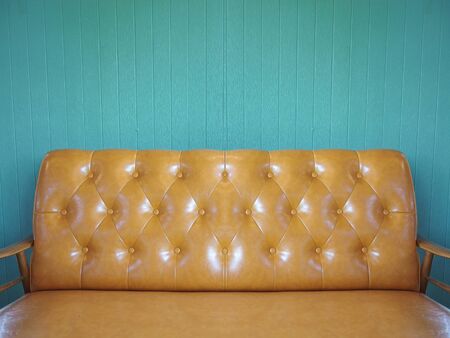 Brown Leather sofa with vintage color wood panel wall as background.