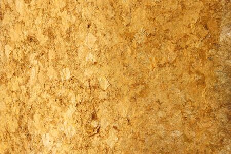 Thai ancient buddha statue back which decorating by small golden paper on surface skin wall background.の写真素材