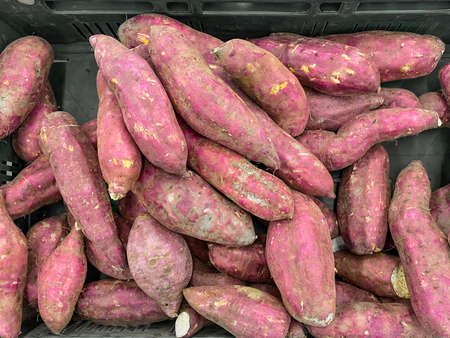 Raw Japanese red potatoes stack for sale in market.