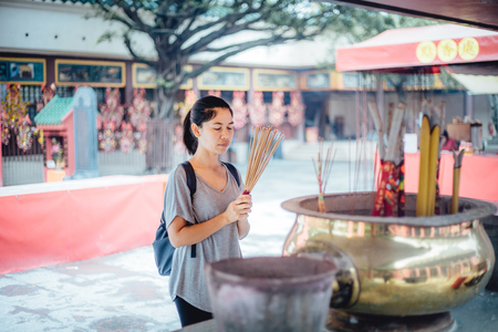 Asian girl praying outdoor at a temple, offering incense sticksのeditorial素材