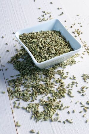 Dried fennel seeds in a bowl on a bright woodの写真素材