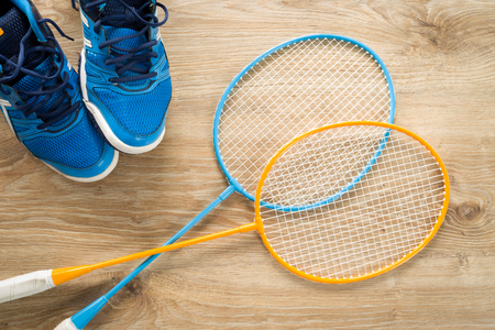 Badminton accessories, shoes and a rocket on a wooden floorの写真素材
