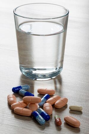 colored pills and a glass of waterの写真素材