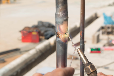 Plumbing contractor works sweating the joints on the copper pipe domestic water system on a luxury custom homeの写真素材