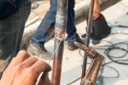 Plumbing contractor works sweating the joints on the copper pipe domestic water system on a luxury...