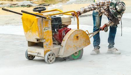 Construction worker cutting Asphalt paving stabs for sidewalk using a cut-off saw. Profile on the...