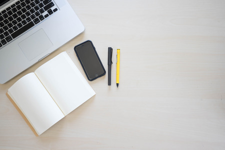 Office table with laptop, book pen , pencils and phoneの写真素材