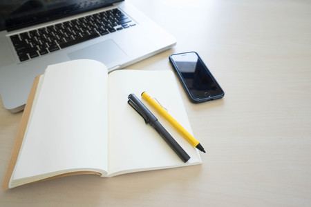 Office table with laptop, book pen , pencils and phoneの写真素材
