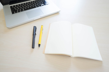 Office table with laptop, book pen , pencils and phoneの写真素材