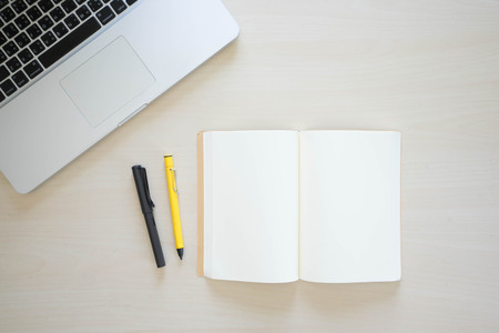 Office table with laptop, book pen , pencils and phoneの写真素材
