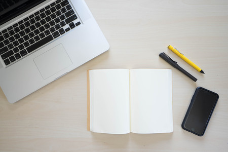Office table with laptop, book pen , pencils and phoneの写真素材