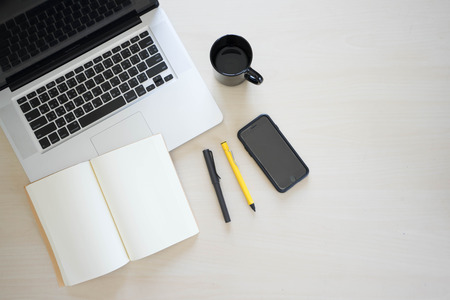 Office table with laptop, book pen , pencils , phone and cupの写真素材