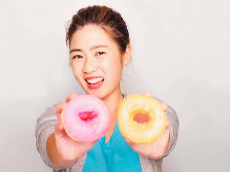 Young beautiful asian woman wore blue t-shirt and gray cardigan holding donut sweets, Smile and enjoy eating doughnut, soft and selective focusの写真素材