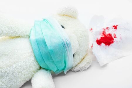health care concept,White bear Wear a protective mask sitting on the floor,with tissues with blood protective mask isolated on red backgroundの写真素材