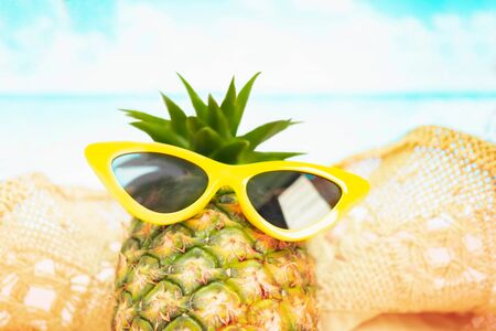 Beach,Funny pineapple in a red sunglasses and hat on the sand against sea and sky.Tropical summer vacation concept. Sunny day on the beach,Selective focus yellow and blue seaの写真素材