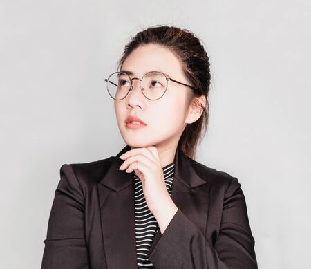 Young smart beautiful asian business woman wore black suit and glasses,smart and thinking holding...