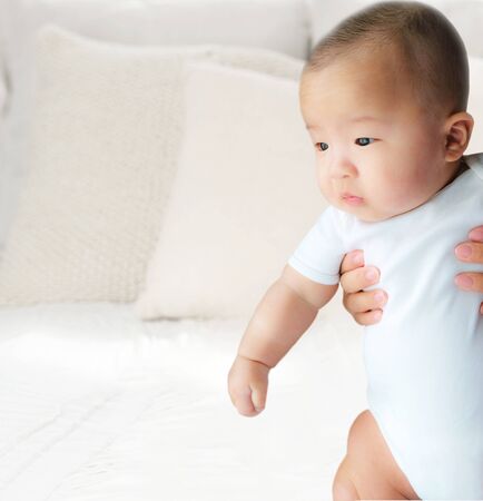 Portrait of a newborn Asian baby boy on the bed , Charming Fat baby 5 month old lies in bed looking with copy space,,soft and selective focusの写真素材