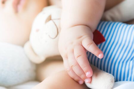 cropped hand of baby hug a doll in bedroom while sleeping ,soft selective focusの写真素材