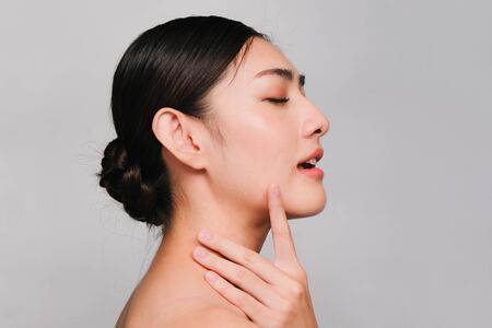 Beautiful asian woman ,young asian girl with clean and bright skin, Cosmetic Beauty Concept,hands touch on the cheek,smily and friendly face isolated on grey backgroundの写真素材
