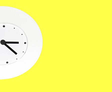 white wall clock on yellow background with copy spaceの写真素材