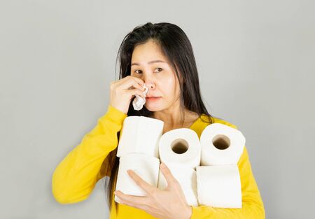 Fever,Young Asian woman wearing yellow shirt,Have a cold, wipe the snot isolated on gray...