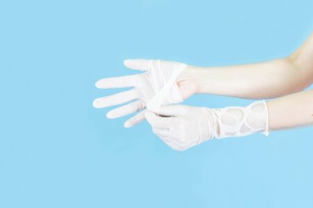 White latex medical gloves on a woman's hand,Taking off gloves isolated on blue backgroundの写真素材