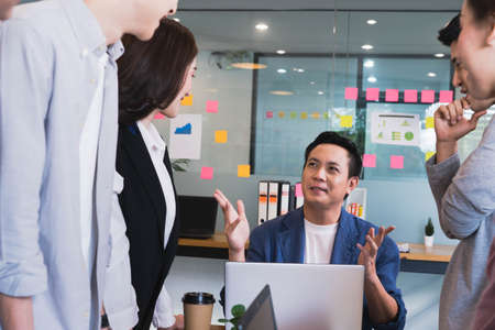 Focus on asian man(boss or manager)standing in group brainstorm meeting in office.Businesspeople...