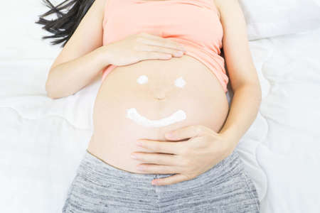 Smiling face shape created from cream on the big belly.の写真素材