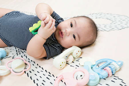 Adorable smiling happy asian baby boy having fun with toys on play mat. Happy healthy kid playing on floor with mobile educational toys. lifestyle concept. authentic childhoodの写真素材