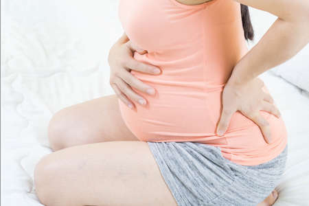 à¹Happy pregnancy mother touch belly. Single mother pregnant 8 month sitting alone outdoor hopeful and care baby in her body.の写真素材