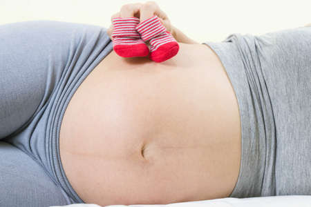 A tummy of a pregnant woman with red baby's bootees,Pregnancy health care preparing for baby...