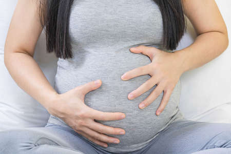 à¹Happy pregnancy mother touch belly. Single mother pregnant 8 month sitting alone outdoor hopeful and care baby in her body.の写真素材