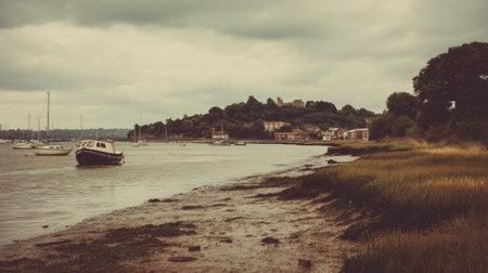 A tranquil coastal scene featuring boats on calm water, lush grass along the shoreline, and a distant hill under a dramatic cloudy sky, perfect for nature lovers.の素材