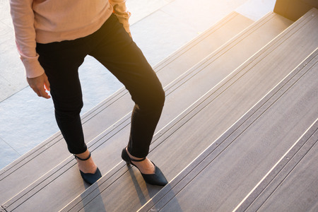 Business woman up the stairs. Female legs in high heels shoes walking on the stairs.の写真素材