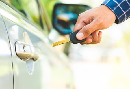 Closeup of a man hand inserting key into the door lock of a car.の写真素材