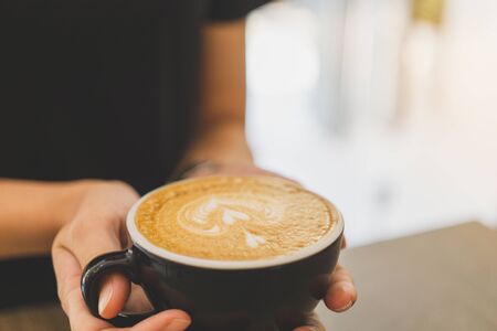 Female hands holding a cup of hot late art.の写真素材