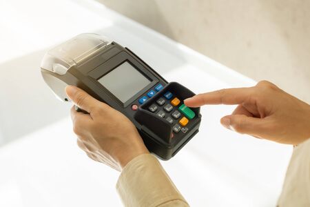 Close up of hand using credit card swiping machine to payment. Cashless paying for shopping concept....
